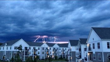 a bolt of lighting strikes the ground behind an apartment complex